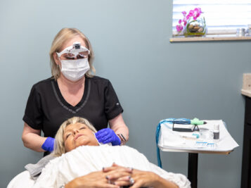 female doctor touching patients head that is laying down