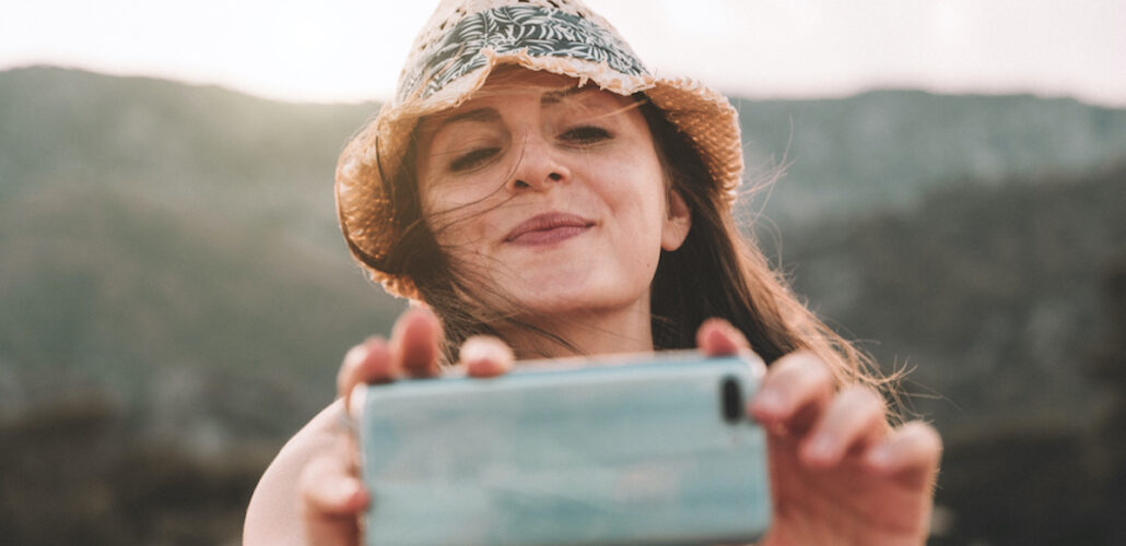 Beautiful smiling girl taking a picture with her smartphone.