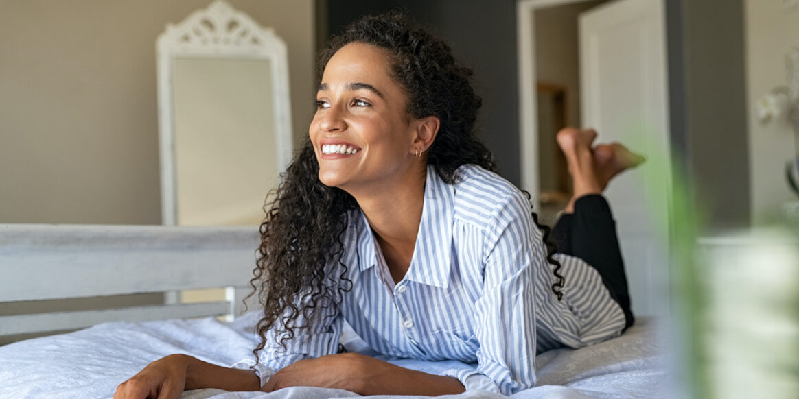 Happy young mixed race woman relaxing on bed