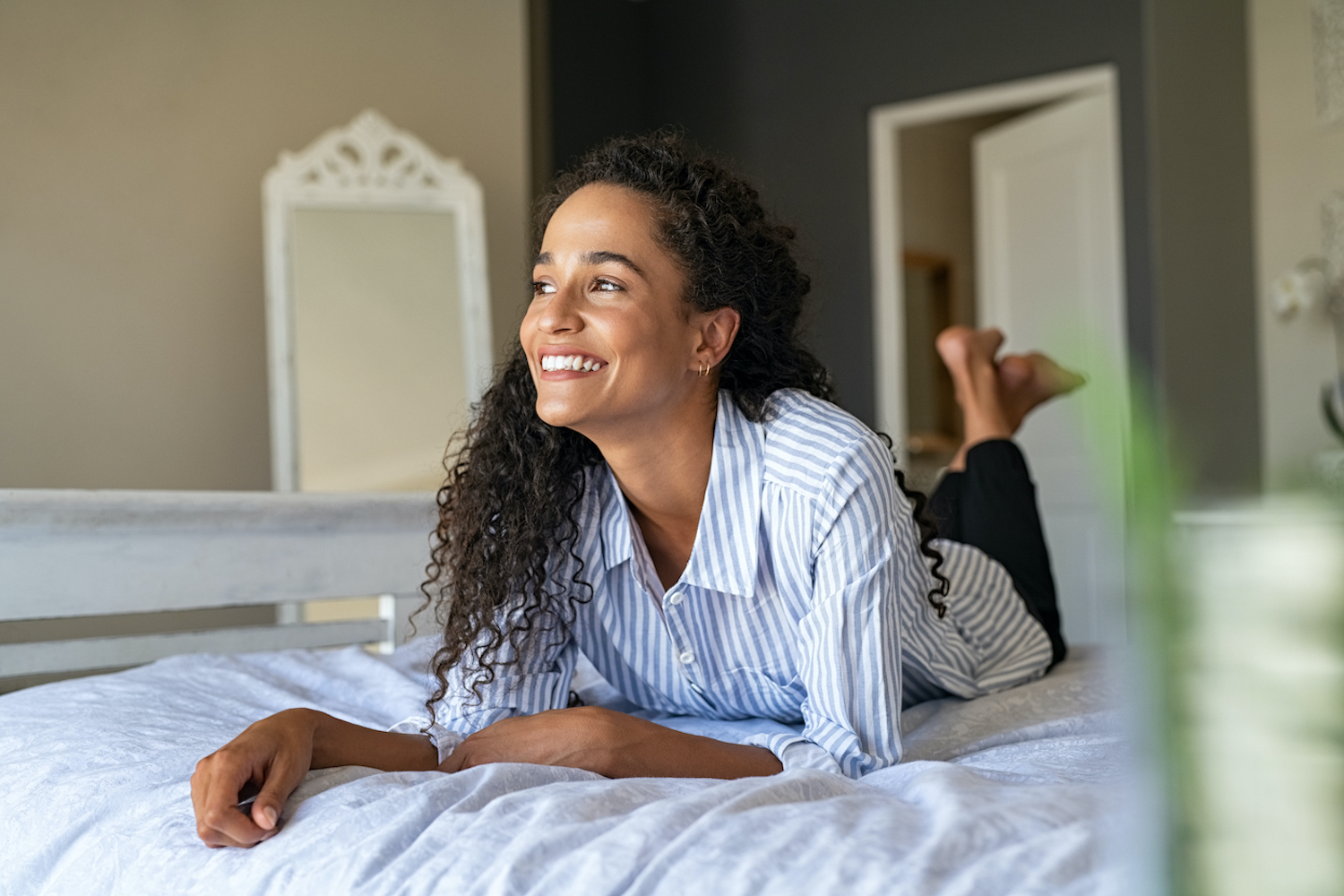 Happy young mixed race woman relaxing on bed