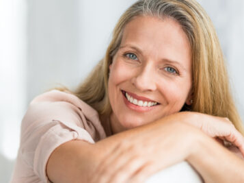 older white women laying on her arms and smiling at the camera