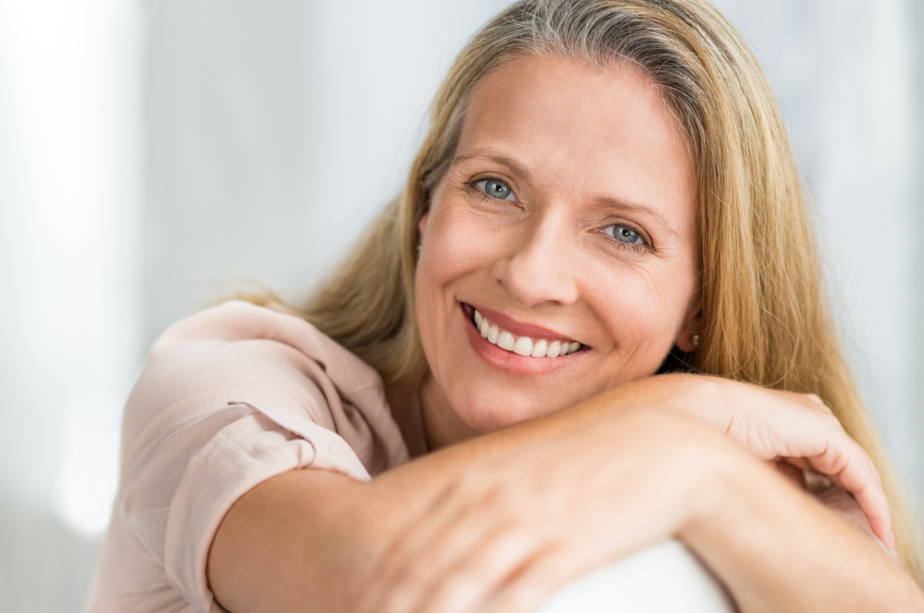 older white women laying on her arms and smiling at the camera