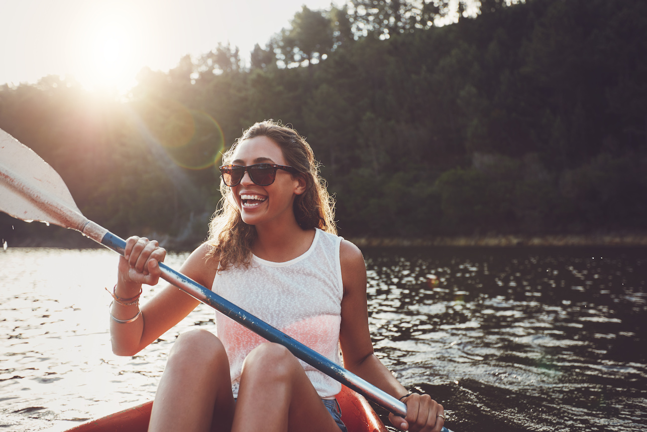 Smiling young woman kayaking on a lake