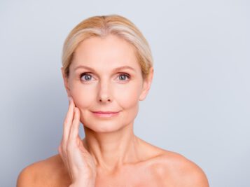 older white women touching her face with a gray background