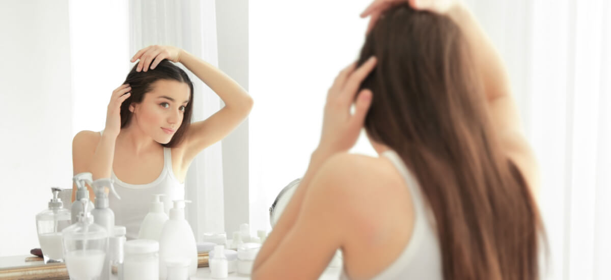 woman doing her hair in a mirror