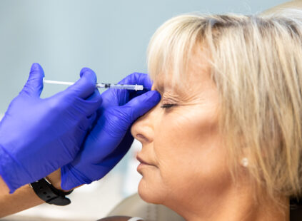 Woman receiving Botox injection near the eye area to reduce wrinkles and fine lines.