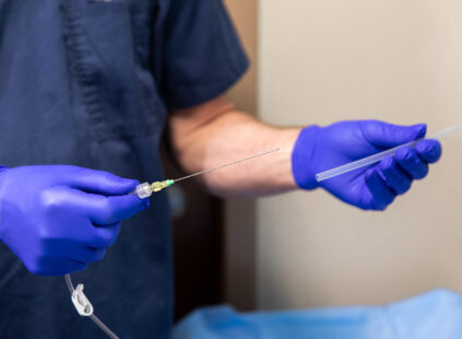 Doctor preparing an injection syringe while wearing blue medical gloves in a clinical setting.