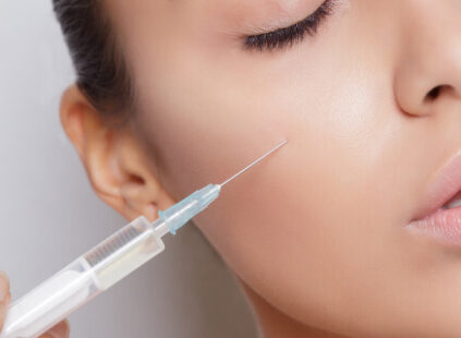 A close-up of a woman receiving a cosmetic injection in her cheek, illustrating dermal filler or aesthetic treatment for facial rejuvenation.