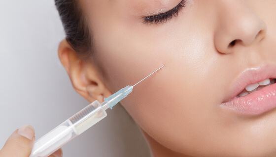 A close-up of a woman receiving a cosmetic injection in her cheek, illustrating dermal filler or aesthetic treatment for facial rejuvenation.