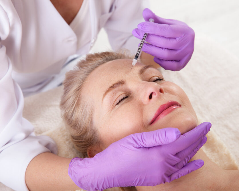 Provider administering a cosmetic injectable treatment to a woman’s forehead at a medical aesthetics clinic.