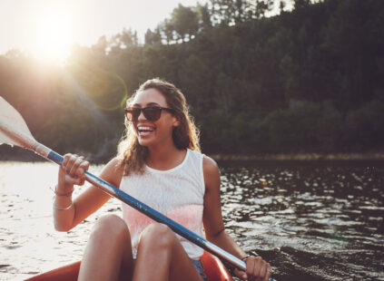 Smiling young woman kayaking on a lake